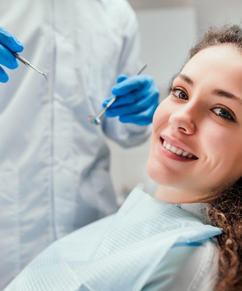 Smiling young woman receiving dental checkup. close up view. Healthcare and medicine concept.